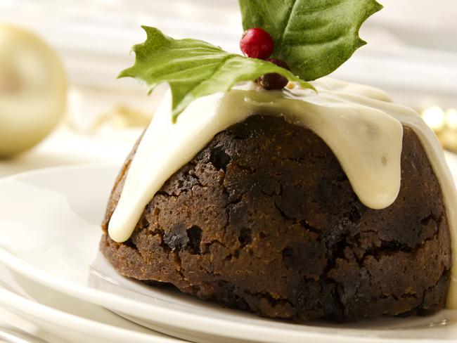 Christmas pudding decorated with holly and drizzled in brandy sauce.