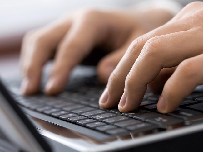 Close-up of male fingers typing a business document on the black laptop