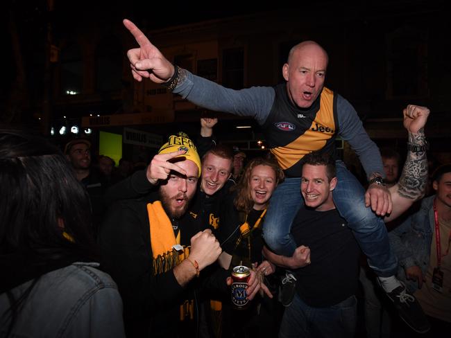 A Tigers supporter gets a piggy back during celebrations along Swan St. Picture: AAP/James Ross