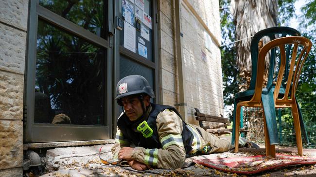 An Israeli firefighter takes cover as sirens sound to warn of rockets launched from southern Lebanon, in Kiryat Shmona in June. Picture: AFP