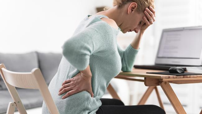 Woman working on a laptop and having headache and back, hip, spine pain.