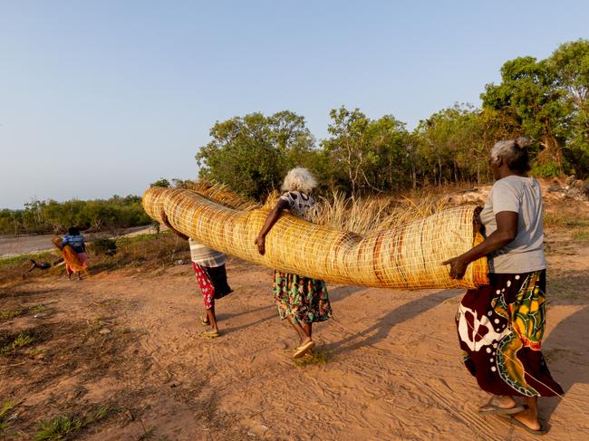 EMBARGO FOR TWAM 21 OCT 2023. FEE MAY APPLY. October 2023: Women from ManingridaÃ¢â¬â¢s Art Centre in the Northern Territory carry their 100m Fish Fence to be loaded onto a barge headed for Darwin on it's way to the National Victoria Art Gallery. Photo: Renae Saxby