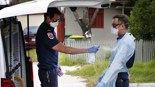 Hamilton is sprayed with disinfectant by a colleague before taking off the PPE after the patient has left the scene. Picture: David Caird