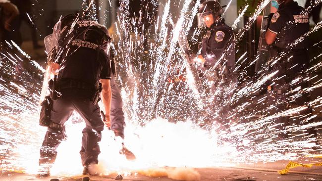 A firecracker thrown by protesters explodes under police in Washington. Picture: AFP