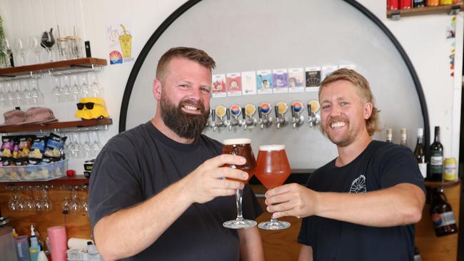 Squinters co-owner Mat Goss, left, and bar manager, Frothy, toast the 100 with beers at the Squinters Brewing CO in Penrith. Picture: Damian Shaw