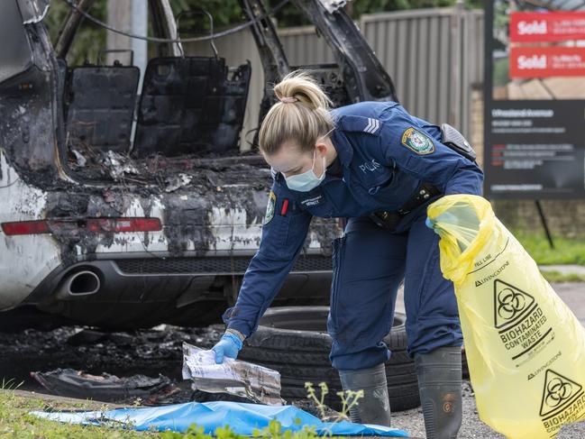 Forensics police officers examine the scene of a burnt out car in a double murder. Picture: NCA NewsWire / Monique Harmer