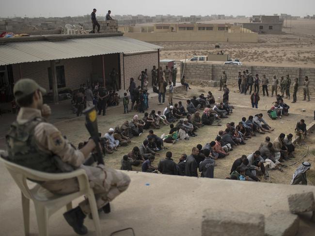 Displaced people who fled from Islamic State-held territory sit outside a mosque guarded by Iraqi soldiers in Shuwayrah, south of Mosul. Picture: AP Photo/Felipe Dana