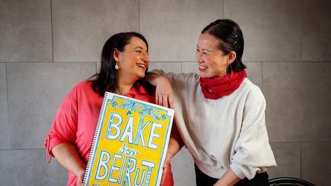 Former MasterChef contestants and friends Rose Adam and Poh Ling Yeow with the cover of Bake for Beirut, which was artistically created by Poh. Picture: Matt Turner