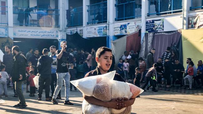 A boy walks with sacks of food supplies through a yard at a school run by the United Nations Relief and Works Agency for Palestine Refugees. PIcture: Said Khatib