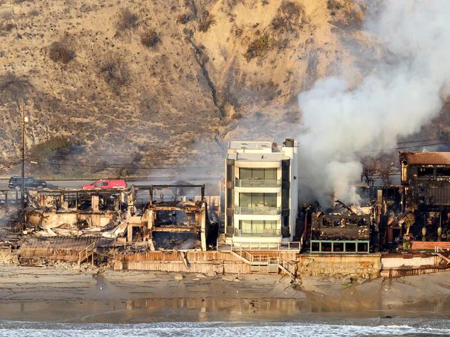 TOPSHOT - In this aerial view taken from a helicopter, burned homes are seen from above during the Palisades fire in Malibu, Los Angeles county, California on January 9, 2025. Massive wildfires that engulfed whole neighborhoods and displaced thousands in Los Angeles remained totally uncontained January 9, 2025, authorities said, as US National Guard soldiers readied to hit the streets to help quell disorder. Swaths of the United States' second-largest city lay in ruins, with smoke blanketing the sky and an acrid smell pervading almost every building. (Photo by JOSH EDELSON / AFP)