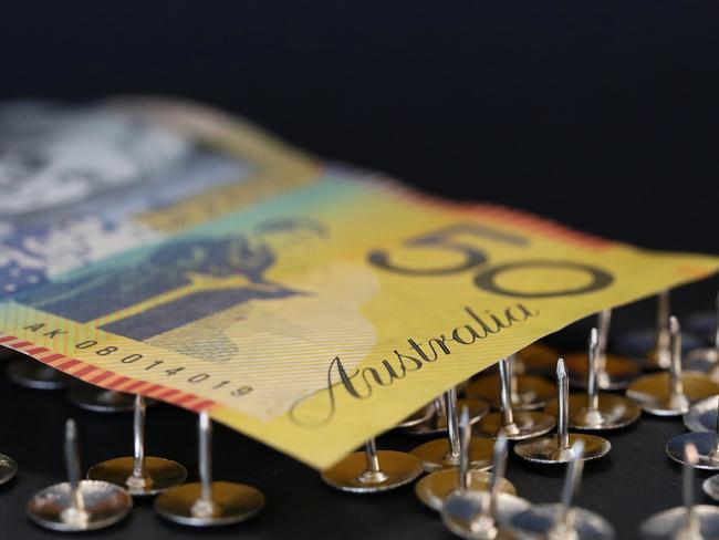 close up extreme shallow depth of field macro shot of australian fifty dollar note supported on sharp thumb tacks or drawing pins. Finance business economy concept. Debt trap generic money