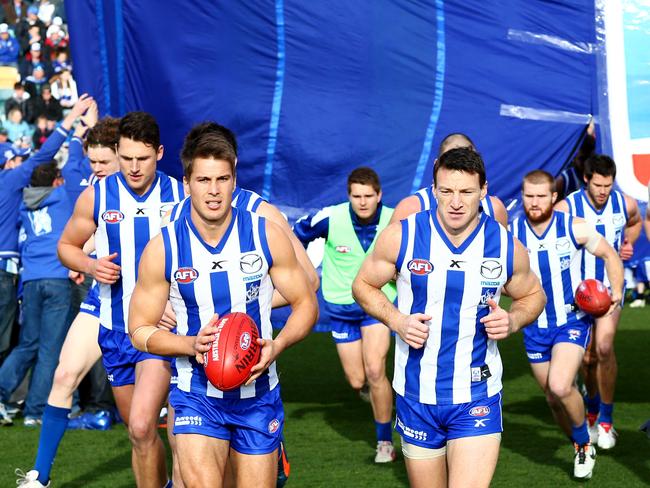 North Melbourne’s Andrew Swallow, left., and Brent Harvey, right, run through the banner at Blundstone Arena.