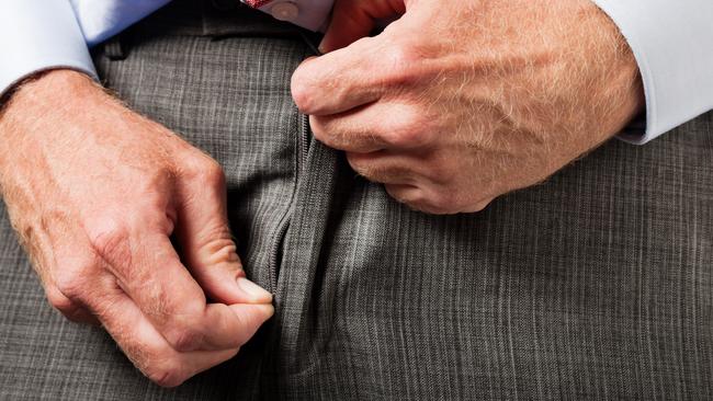 Cropped view of businessman's hands unzipping his trouser fly, hopefully to urinate and not as a flasher!