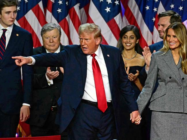 TOPSHOT - -- AFP PICTURES OF THE YEAR 2024 --  Former US President and Republican Presidential candidate Donald Trump gestures at supporters as he holds hands with former US First Lady Melania Trump during an election night event at the West Palm Beach Convention Center, in West Palm Beach, Florida, early on November 6, 2024.Â . Republican former president Donald Trump closed in on a new term in the White House early November 6, 2024, just needing a handful of electoral votes to defeat Democratic Vice President Kamala Harris. (Photo by Jim WATSON / AFP) / AFP PICTURES OF THE YEAR 2024