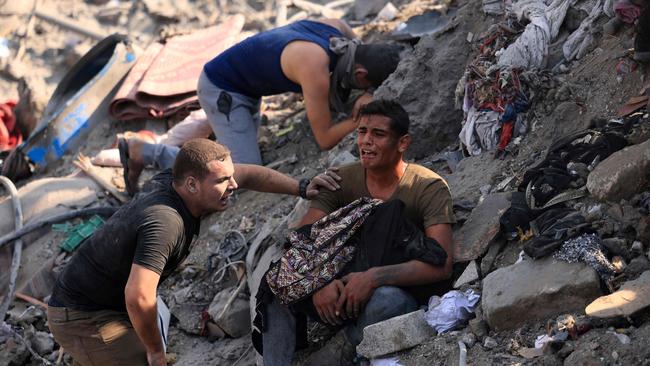 A Palestinian holds the remains of his mother amid the rubble of building destroyed in an Israeli strike on the Bureij refugee camp on Thursday. Picture: AFP