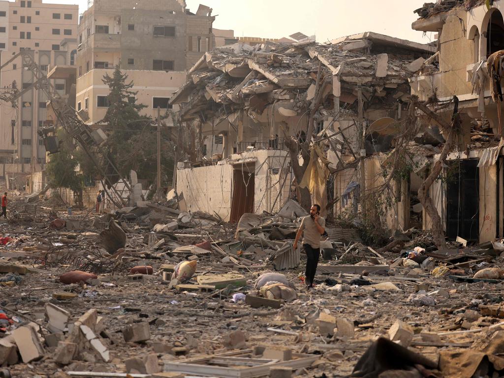 A Palestinian man talks on his mobile phone as he walks through a ravaged street following Israeli air strikes on Gaza City. Picture: AFP