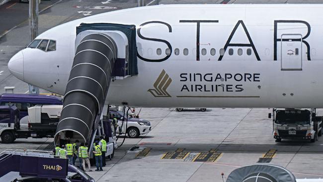 Officials enter the Singapore Airlines Boeing 777-300ER airplane, which was headed to Singapore from London before making an emergency landing in Bangkok due to severe turbulence, as it is parked on the tarmac at Suvarnabhumi International Airport in Bangkok on May 22, 2024. A 73-year-old British man died and more than 70 people were injured on May 21 in what passengers described as a terrifying scene aboard Singapore Airlines flight SQ321 that hit severe turbulence, triggering an emergency landing in Bangkok. (Photo by Lillian SUWANRUMPHA / AFP)