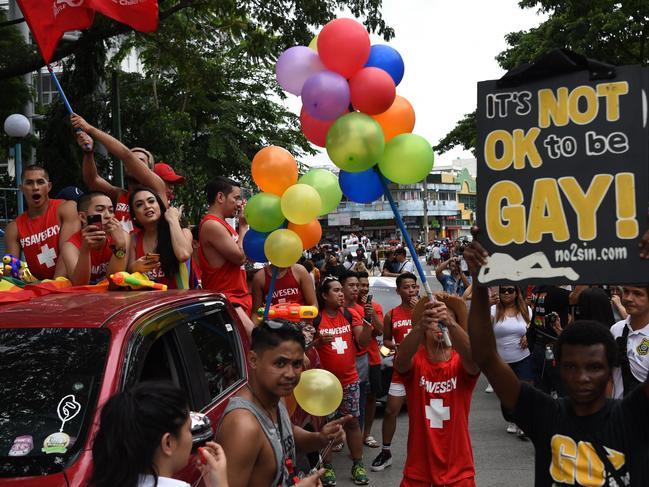 Members of LGBTQ community walk past a man holding a placard, protesting against the pride march in Marikina City, east of Manila. Picture: AFP