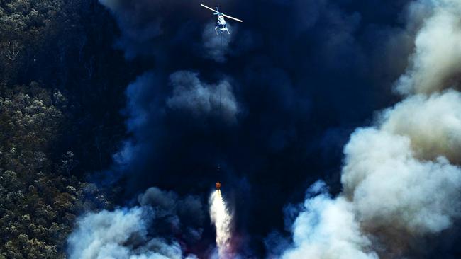 Water bombing Helicopter tackles the thick smoke of an out of control bushfire travelling from Peregian Beach towards Weyba Downs. Picture: Lachie Millard