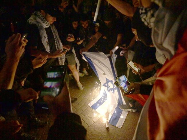 Protesters at Rally For A Free Palestine burn the Israeli flag on the forecourt of The Sydney Opera House. Picture: Jeremy Piper