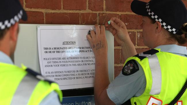 Police use metal detectors to search random people during a crackdown on concealed weapons.