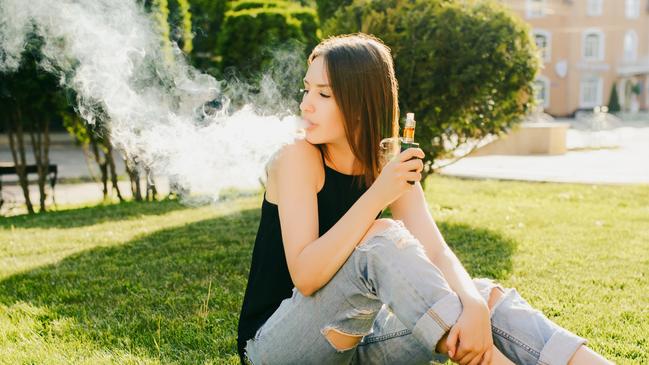 Girl smokes vape.