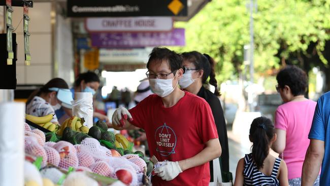 Ken Liang, a shop assistant at a Chinese grocery in Eastwood sorting fruit shelves in the s Shopping precinct along Rowe St where people on the street are wearing masks as a safeguard. Picture: Britta Campion/The Australian