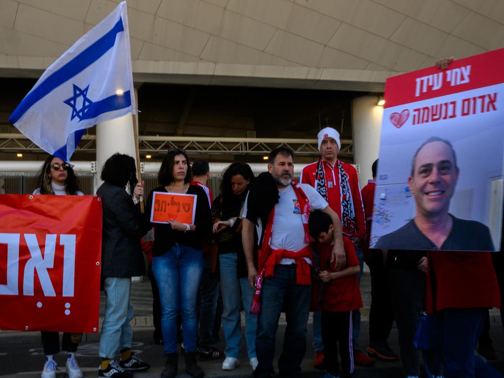 A woman holds an Israeli flag and a sign with the words "Sorry" in hebrew while lining the street as the procession carrying former Israeli hostage Tsachi Idan leaves for the funeral. Picture: Alexi J. Rosenfeld/Getty Images