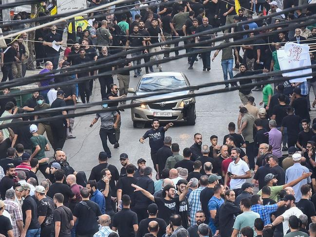 TOPSHOT - People react around a car after a reported explosion occurred during the funeral of those killed when hundreds of paging devices exploded across Lebanon the previous day, in Beirutâs southern suburbs on September 18, 2024. A second wave of device explosions killed three people in Hezbollah strongholds of Lebanon on September 18, raising fears of an all-out war between Israel and the Iran-backed militants. (Photo by Fadel ITANI / AFP)