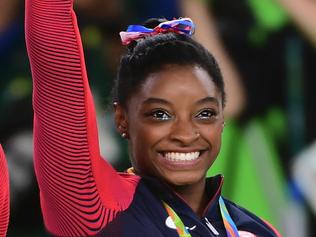 US gymnast Simone Biles celebrates on the podium during the women's team final Artistic Gymnastics at the Olympic Arena during the Rio 2016 Olympic Games in Rio de Janeiro on August 9, 2016. / AFP PHOTO / Emmanuel DUNAND