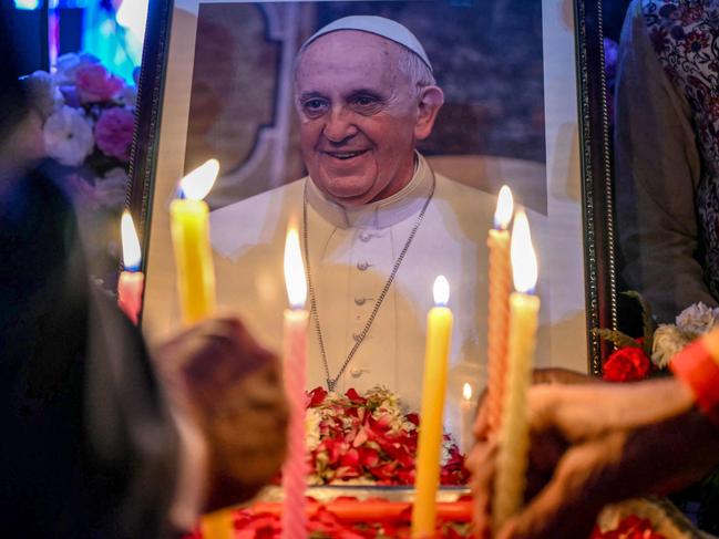 TOPSHOT - People light candles as they pay respects in front of a portrait of Pope Francis during a condolence meeting in New Delhi on April 21, 2025, following the news of his death. Pope Francis, an energetic reformer who inspired widespread devotion from Catholics but riled traditionalists, died on April 21, aged 88, just a day after greeting delighted worshippers after Easter Mass. (Photo by Sajjad HUSSAIN / AFP)