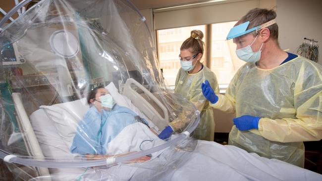 ICU specialist Prof Forbes McGain speaks to a patient through a new protective hood. Picture: Tony Gough