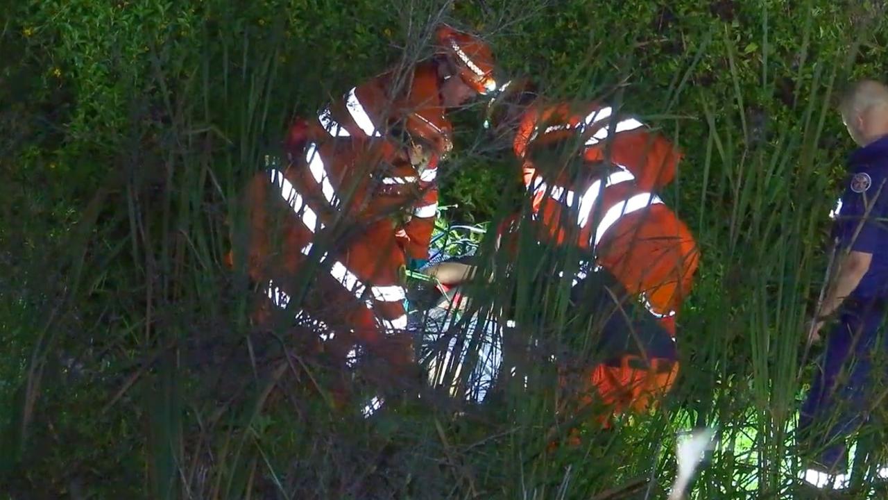 Emergency service workers help a man after a crash that happened in an exit lane from the Pacific Highway at Moonee Beach on March 9, 2022.