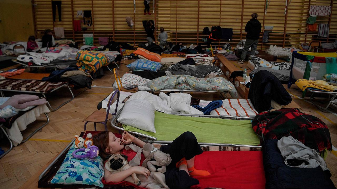 A girl rests with her dog in their temporary shelter in the gym of a primary school in Przemysl, in southeastern Poland. Picture: Louisa Gouliamaki/AFP