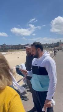 Two men rip down posters of missing Israelis at a Bondi Beach memorial