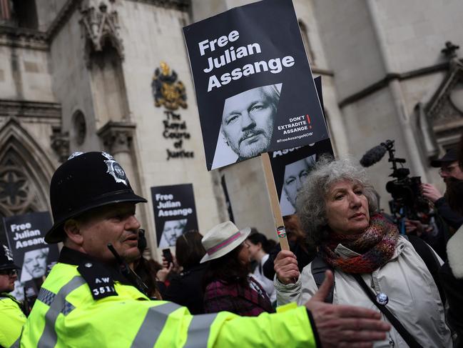 Police officers stand guard as supporters of WikiLeaks founder Julian Assange hold placards outside The Royal Courts of Justice, Britain's High Court, in central London. Picture: AFP