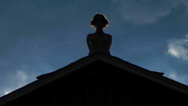 The artist Poppy Jackson sitting on a barn roof for her piece called Hay Barn. Picture: Facebook/Poppy Jackson