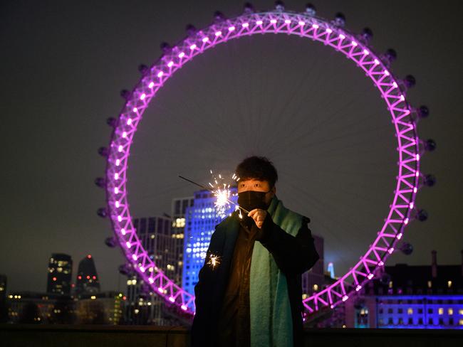 A man holds a sparkler in front of the London Eye, in what would normally be a ticket-only area filled to capacity waiting for the annual fireworks display. Picture: Getty