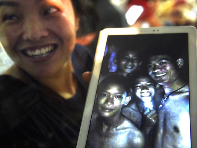 CORRECTION - Thanaporn Promthep, mother of one of the 12 missing boys, displays an image believed to have been taken in 2017 of her son Duangpetch Promthep, nicknamed "Dom" (pictured 2nd R-with light) and his football coach Ekkapol Chantawong (R), after hearing the news the group was found, near the Tham Luang cave at the Khun Nam Nang Non Forest Park in the Mae Sai district on July 2, 2018. Twelve boys and their football coach trapped in a flooded Thai cave for nine days were "found safe" on late July 2, in a miracle rescue after days of painstaking searching by divers. The two boys at L are not trapped in the cave. / AFP PHOTO / LILLIAN SUWANRUMPHA / “The erroneous mention[s] appearing in the metadata of this photo by LILLIAN SUWANRUMPHA has been modified in AFP systems in the following manner: [clarifying information, as well as adding names]. Please immediately remove the erroneous mention[s] from all your online services and delete it (them) from your servers. If you have been authorized by AFP to distribute it (them) to third parties, please ensure that the same actions are carried out by them. Failure to promptly comply with these instructions will entail liability on your part for any continued or post notification usage. Therefore we thank you very much for all your attention and prompt action. We are sorry for the inconvenience this notification may cause and remain at your disposal for any further information you may require.”