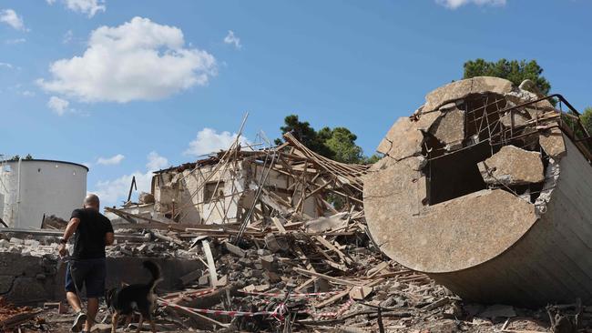 A man walks with a dog past a the rubble of a destroyed building in Hod HaSharon in the aftermath of an Iranian missile attack on Israel, on October 2, 2024. Israel vowed to make Iran "pay" for firing a barrage of missiles at its territory, with Tehran warning on October 2 it would launch an even bigger attack it is targeted. (Photo by Jack GUEZ / AFP)