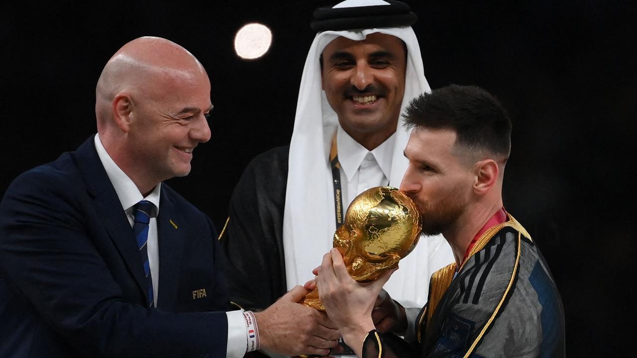 Argentina's forward #10 Lionel Messi kisses the World Cup trophy as FIFA President Gianni Infantino and Qatar's Emir Sheikh Tamim bin Hamad al-Thani look on during the Qatar 2022 World Cup trophy ceremony.