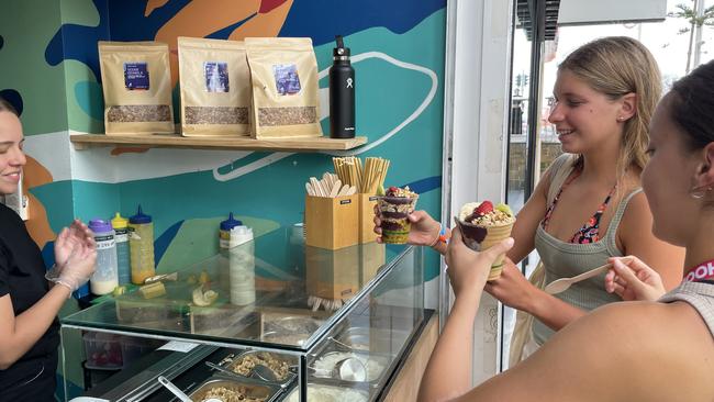 Schoolie twins Charlotte and Olivia Hansen (right) picking up their acai. Picture: Georgina Noack