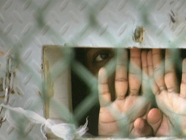 A detainee peers from his cell in the Camp Delta detention facility on Guantanamo Bay US Naval Base in Cuba in 2006. Source: AP