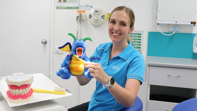 Cairns and Hinterland Health and Hospital Service oral health team leader Stephanie Wallace demonstrates how to brush teeth on a dragon prop, to help children understand the importance of oral hygiene. Photo: Catherine Duffy.