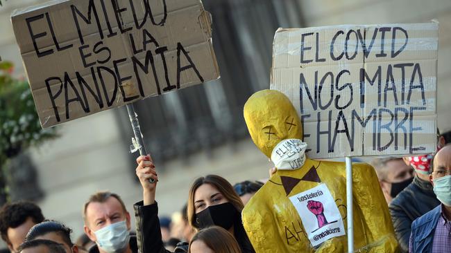 Demonstrators hold placards reading "COVID starves us" and "Fear is the pandemic" as they protest outside the Generalitat (Catalan regional government headquarters) during a demonstration on Friday in Barcelona.