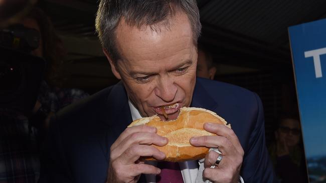 Dirty tricks sure work up an appetite. Leader of the Opposition Bill Shorten tucks in to a sausage sandwich at Sydney’s Strathfield North Public School polling booth on Election Day. (Pic: AAP Image/Mick Tsikas)