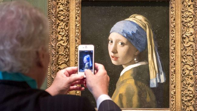 A visitor takes a picture of the "Girl with a Pearl" artwork by painter Johannes Vermeer during a press preview at the renovated Mauritshuis museum in the Hague, the Netherlands, on June 20, 2014. The museum will officially re-open to the public on June 27 after two years of renovations. AFP PHOTO / ANP / LEX VAN LIESHOUT ***Netherlands out*** == RESTRICTED TO EDITORIAL USE, MANDATORY CREDIT OF THE ARTIST, TO ILLUSTRATE THE EVENT AS SPECIFIED IN THE CAPTIONS ==