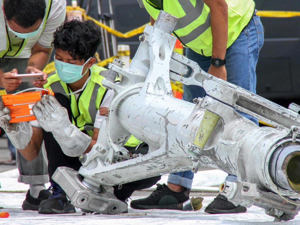 Lion Air investigators examine part of the landing gear of the ill-fated Lion Air flight JT 610 at the port in northern Jakarta. Picture: AFP