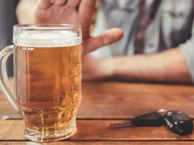 Do not drink and drive! Cropped image of man showing stop gesture and refusing to drink beer. Car keys lying near