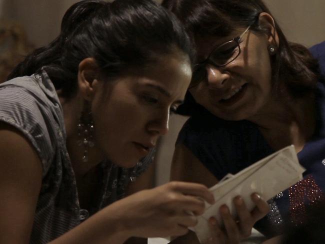 Film maker Lissette Orozco looks at photos from the past with her aunt Adriana Rivas in a scene from the documentary Adriana's Pact.